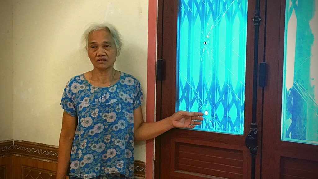 B&agrave; Dư Thị Th&agrave;nh v&agrave; vết đạn bắn tr&ecirc;n cửa k&iacute;nh. Ảnh: May/Luật Khoa.