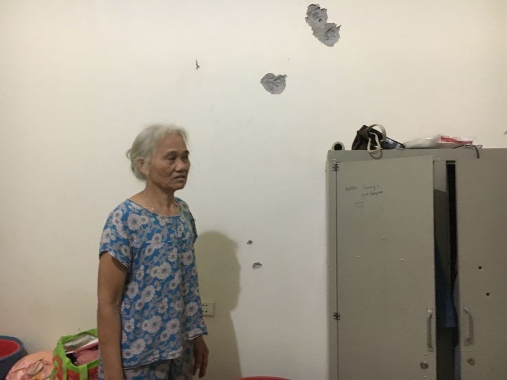 B&agrave; Dư Thị Th&agrave;nh v&agrave; những vết đạn bắn hằn l&ecirc;n tường nh&agrave;. Ảnh: May/Luật Khoa.